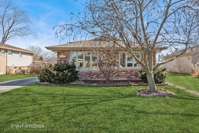 bungalow-style home with a front yard, brick siding, and driveway