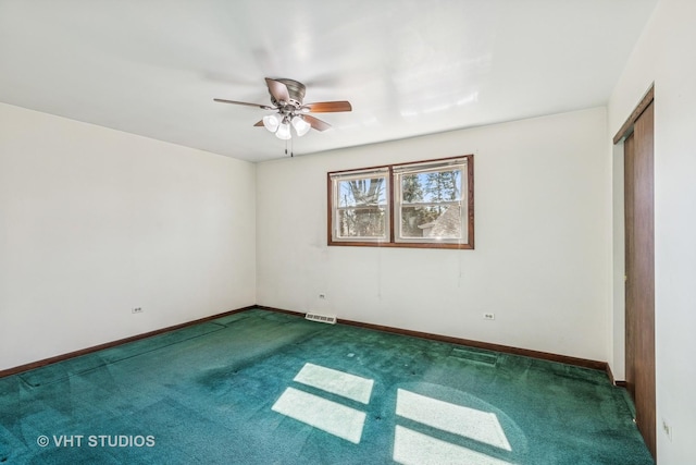 carpeted spare room featuring ceiling fan, visible vents, and baseboards