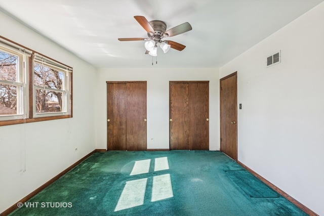 unfurnished bedroom with carpet, multiple closets, visible vents, ceiling fan, and baseboards