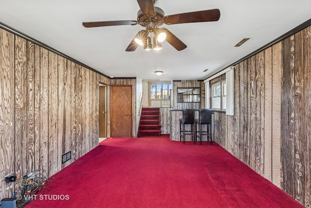 spare room featuring a bar, stairs, wooden walls, and carpet flooring