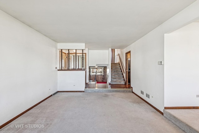 unfurnished living room with stairway, carpet flooring, visible vents, and baseboards