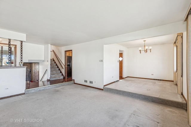 unfurnished living room with a chandelier, stairway, carpet, and baseboards