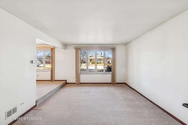 carpeted spare room featuring visible vents and baseboards