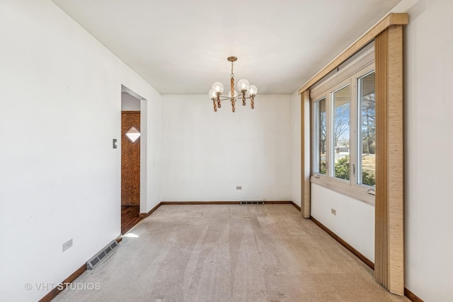 empty room featuring baseboards, light colored carpet, visible vents, and an inviting chandelier