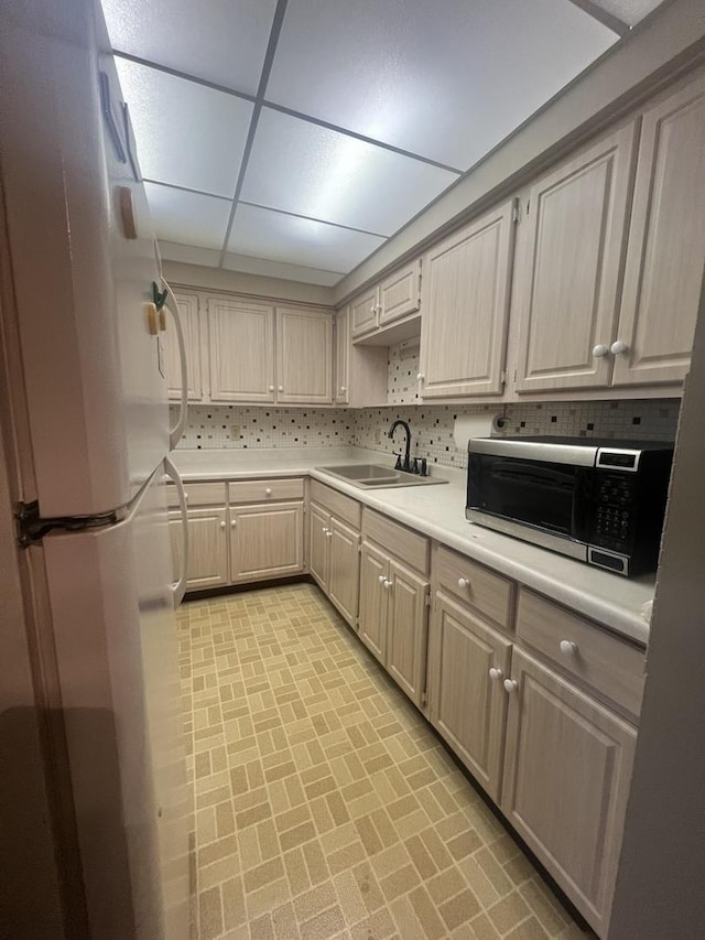 kitchen featuring white refrigerator, sink, tasteful backsplash, and a drop ceiling