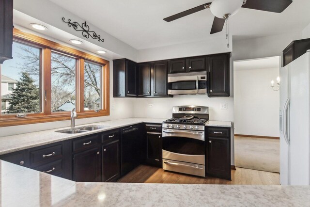 kitchen featuring sink, light stone counters, wood-type flooring, decorative light fixtures, and stainless steel appliances