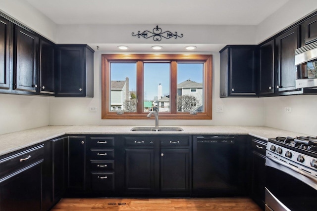 kitchen with light stone counters, appliances with stainless steel finishes, light hardwood / wood-style floors, and sink