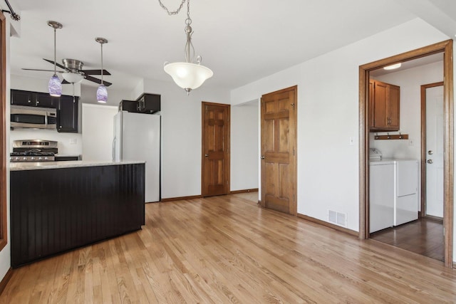 kitchen featuring pendant lighting, ceiling fan, stainless steel appliances, separate washer and dryer, and light wood-type flooring