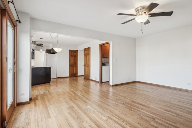 unfurnished living room featuring washer / dryer, light hardwood / wood-style flooring, and ceiling fan