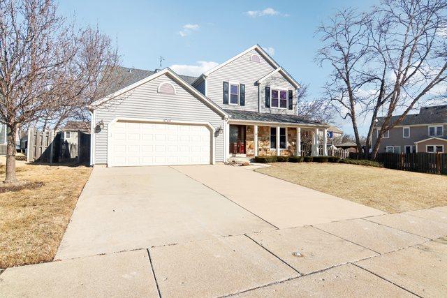 view of property featuring a porch, a garage, and a front lawn