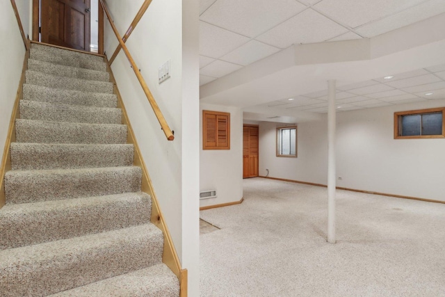 stairway featuring a paneled ceiling and carpet