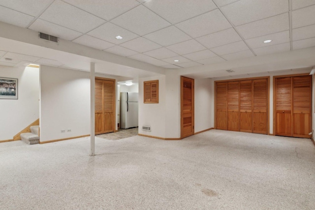 basement with light carpet, a drop ceiling, and stainless steel fridge