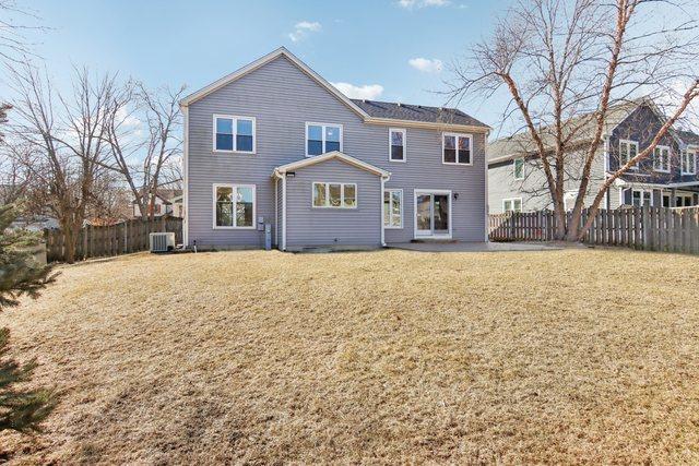 back of property featuring central AC unit and a lawn