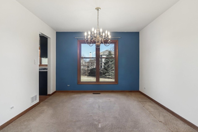 carpeted spare room with a chandelier