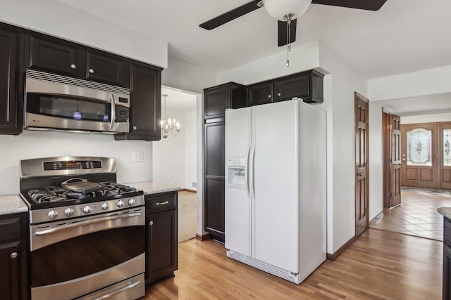 kitchen featuring decorative light fixtures, light hardwood / wood-style flooring, appliances with stainless steel finishes, light stone countertops, and ceiling fan with notable chandelier