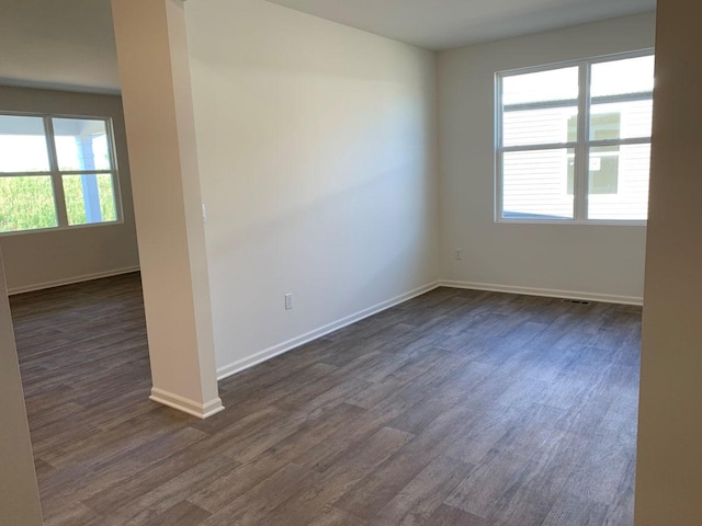 unfurnished room with dark wood-type flooring and a healthy amount of sunlight