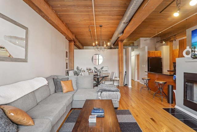 living room featuring beamed ceiling, wooden ceiling, an inviting chandelier, and light hardwood / wood-style flooring