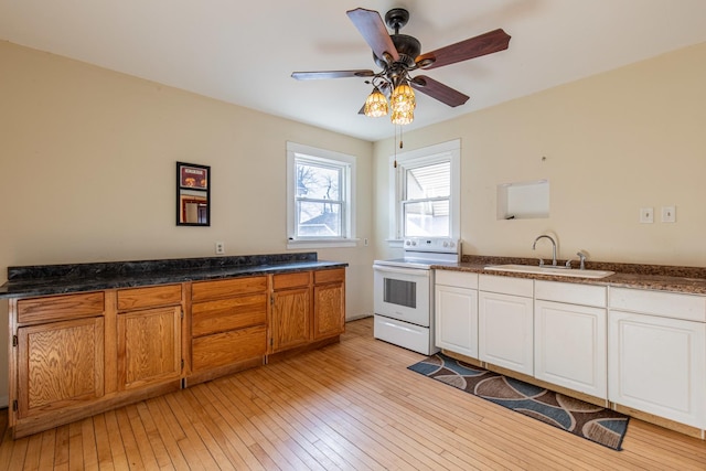 kitchen featuring white electric range oven, sink, white cabinetry, light hardwood / wood-style flooring, and ceiling fan