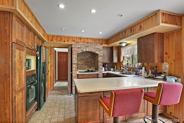kitchen featuring black appliances, light countertops, a peninsula, a sink, and recessed lighting