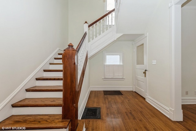 staircase with hardwood / wood-style flooring and a high ceiling