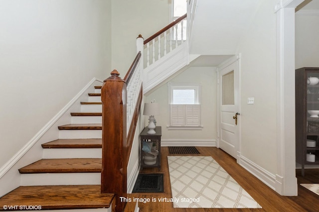 stairway featuring hardwood / wood-style flooring and a high ceiling