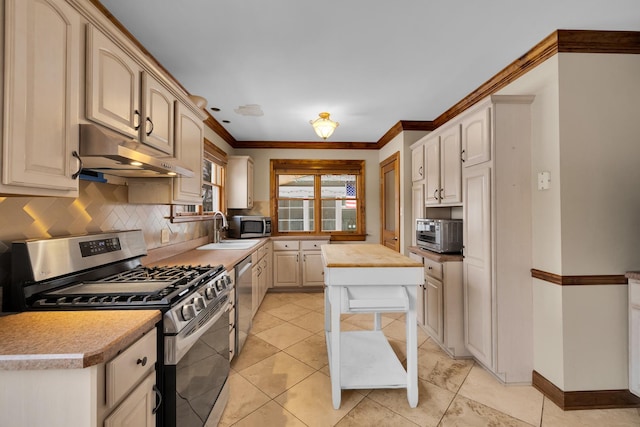 kitchen with sink, crown molding, light tile patterned floors, stainless steel appliances, and decorative backsplash