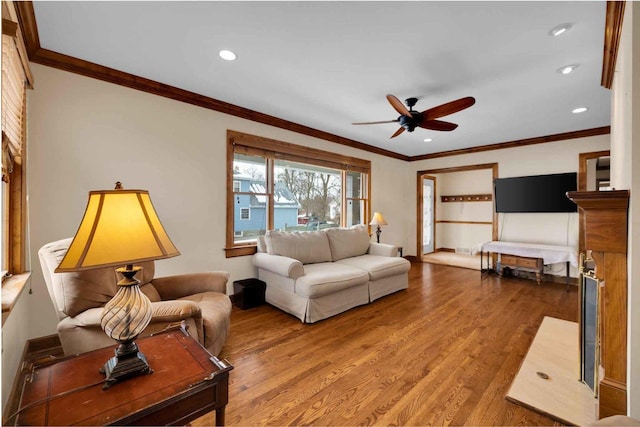 living room with wood-type flooring, ornamental molding, and ceiling fan