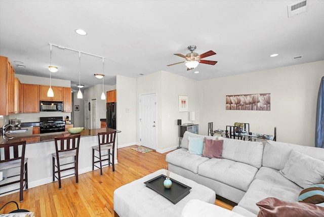 living room with baseboards, visible vents, a ceiling fan, light wood-style floors, and recessed lighting