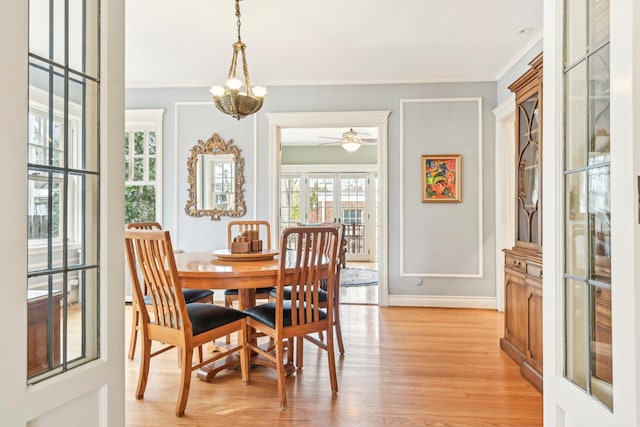 dining space featuring ornamental molding, light wood-type flooring, baseboards, and an inviting chandelier