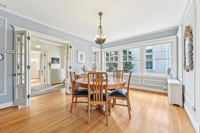 dining space featuring light wood finished floors, radiator heating unit, an inviting chandelier, ornamental molding, and baseboards