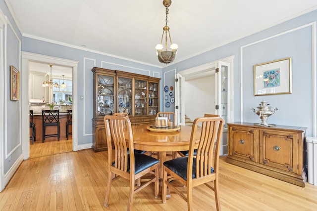 dining room featuring a chandelier, light wood-style flooring, and crown molding