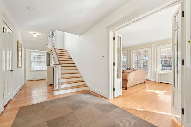 entrance foyer featuring stairway, radiator heating unit, plenty of natural light, and wood finished floors