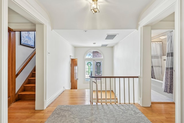 entryway featuring light wood-type flooring, stairs, visible vents, and crown molding