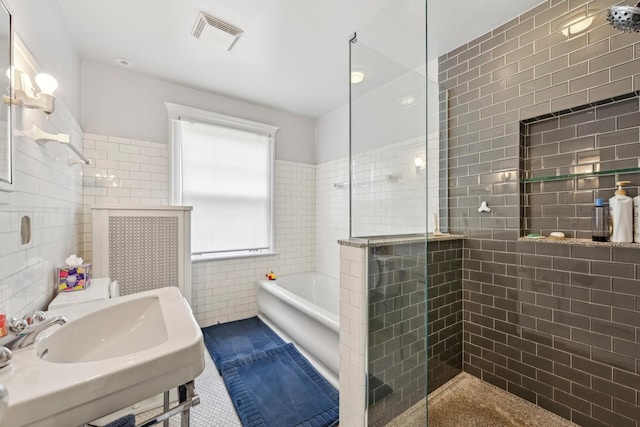 full bathroom featuring a stall shower, visible vents, a garden tub, and tile walls