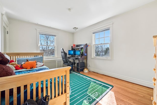 bedroom featuring ornamental molding, radiator heating unit, wood finished floors, and baseboards