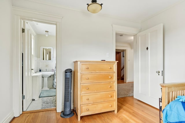 bedroom with crown molding, ensuite bath, and light wood finished floors