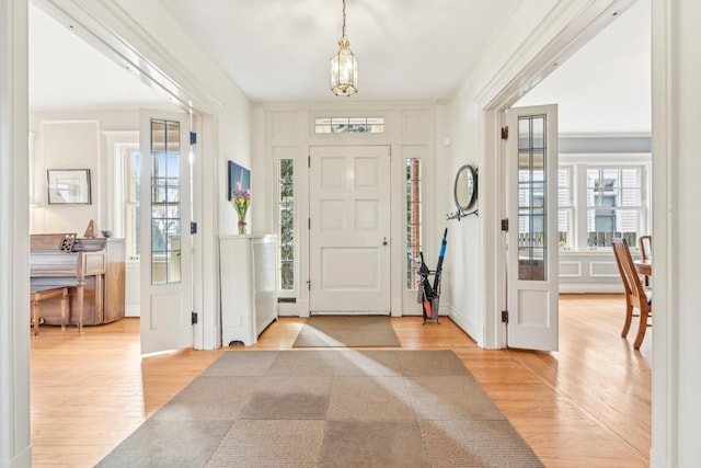 entrance foyer featuring baseboards, light wood-style flooring, and an inviting chandelier