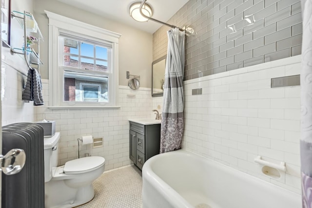 bathroom with tile patterned flooring, toilet, vanity, tile walls, and shower / bath combo