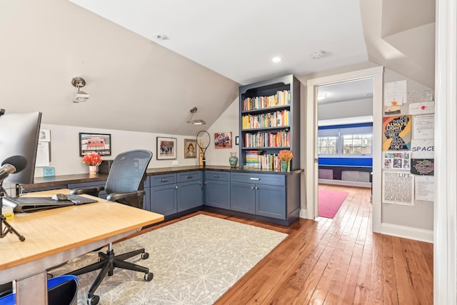 office featuring light wood-type flooring, vaulted ceiling, and baseboards