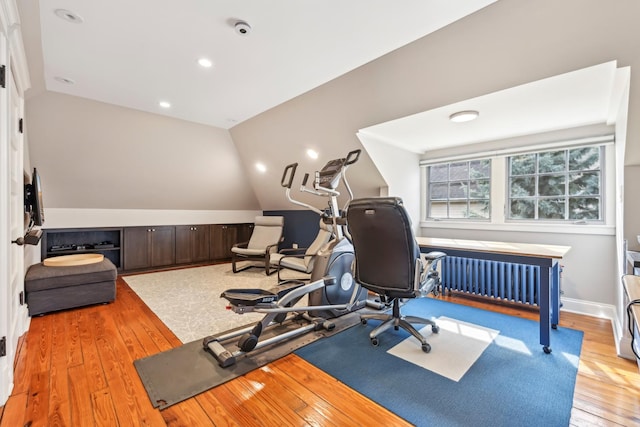 exercise area featuring lofted ceiling, radiator, recessed lighting, light wood-style floors, and baseboards