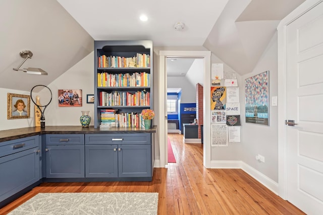 unfurnished office featuring light wood-type flooring, baseboards, and lofted ceiling