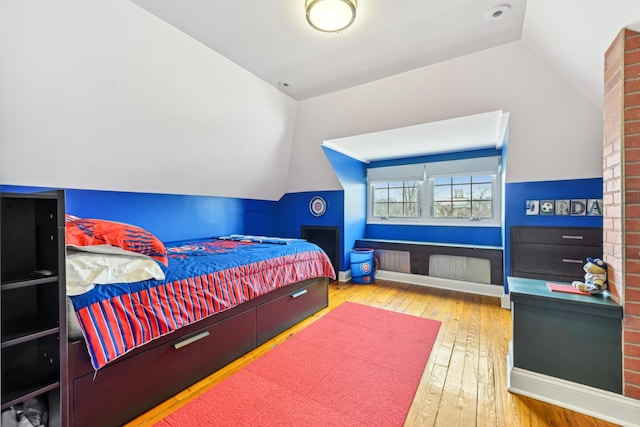 bedroom with lofted ceiling, wood-type flooring, and baseboards