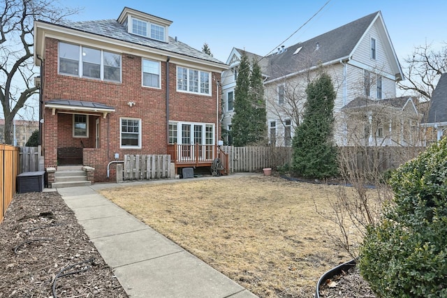 back of property featuring brick siding, a lawn, and fence