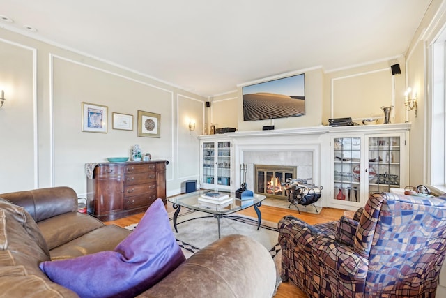 living area with wood finished floors and a glass covered fireplace