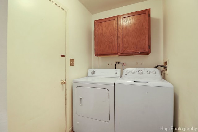 clothes washing area featuring cabinets and washer and clothes dryer