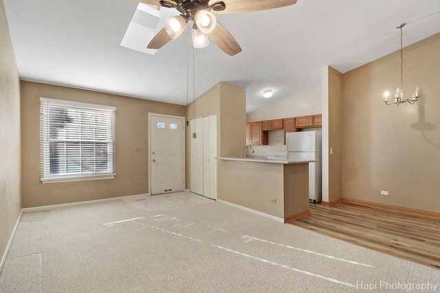 kitchen with sink, vaulted ceiling, white refrigerator, kitchen peninsula, and pendant lighting