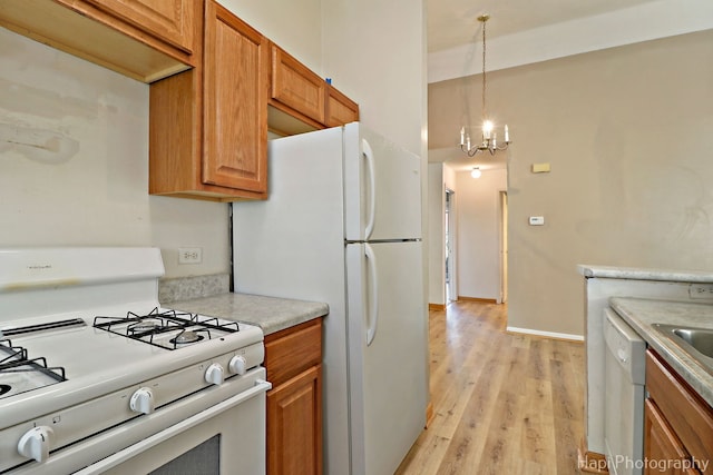 kitchen featuring a chandelier, pendant lighting, white appliances, and light hardwood / wood-style floors