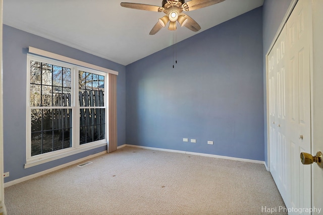 carpeted empty room featuring vaulted ceiling and ceiling fan