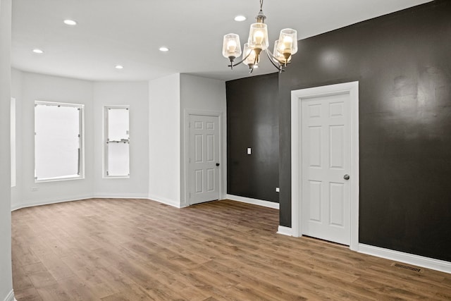 spare room with hardwood / wood-style flooring and an inviting chandelier