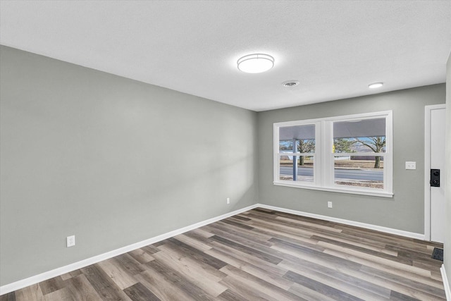 empty room with wood-type flooring and a textured ceiling